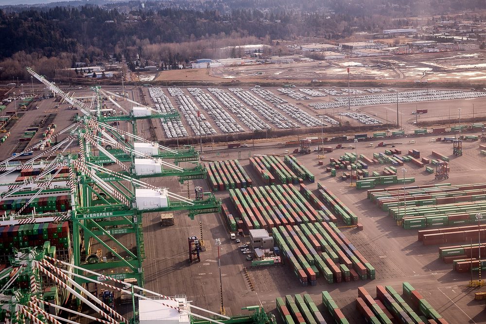 Aerial view of a container terminal with gantry cranes and rows of stacked containers on chassis